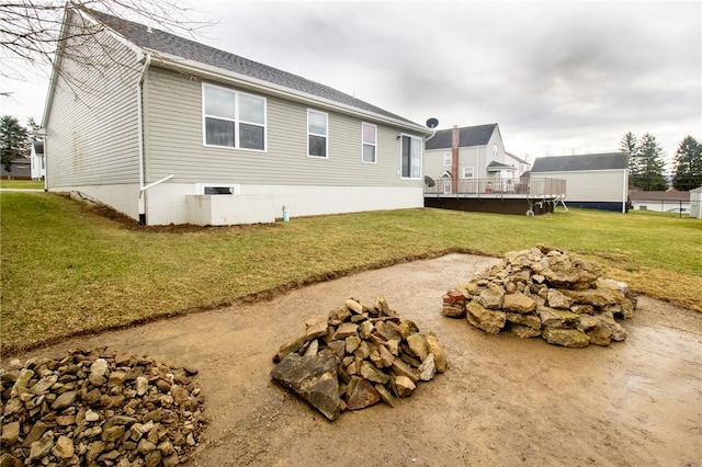 view of side of home featuring an outdoor fire pit and a lawn