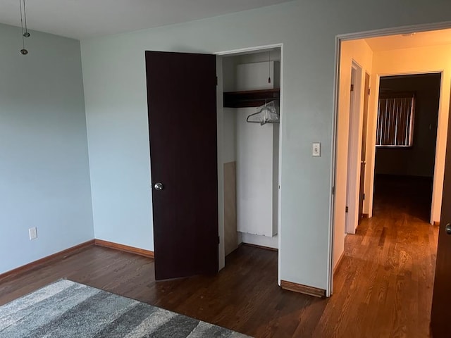 unfurnished bedroom featuring a closet and dark wood-type flooring