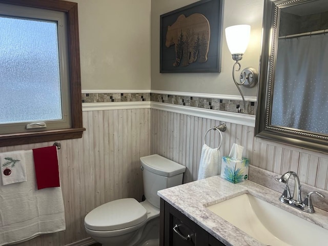 bathroom with vanity, toilet, and wooden walls