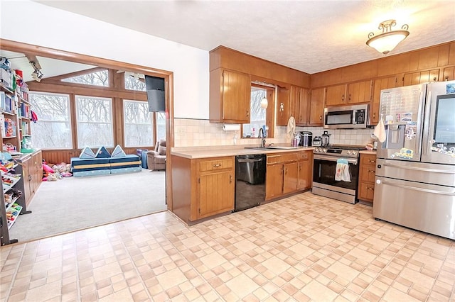 kitchen featuring backsplash, light carpet, sink, a textured ceiling, and stainless steel appliances