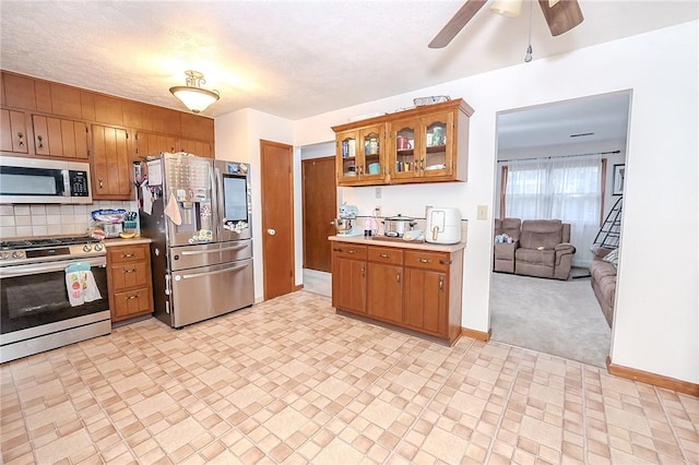 kitchen featuring tasteful backsplash, ceiling fan, light colored carpet, and appliances with stainless steel finishes