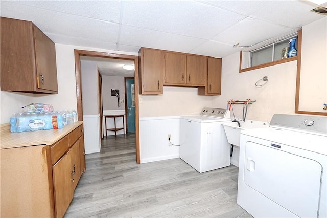 washroom featuring cabinets, independent washer and dryer, light wood-type flooring, and sink