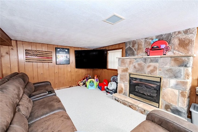 living room with a fireplace, carpet, a textured ceiling, and wood walls