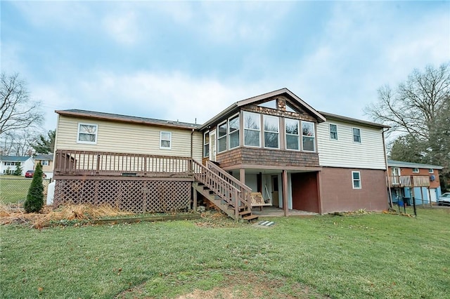 rear view of house with a lawn, a wooden deck, and a sunroom