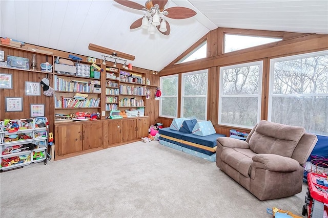 living area with wooden walls, plenty of natural light, carpet, and lofted ceiling