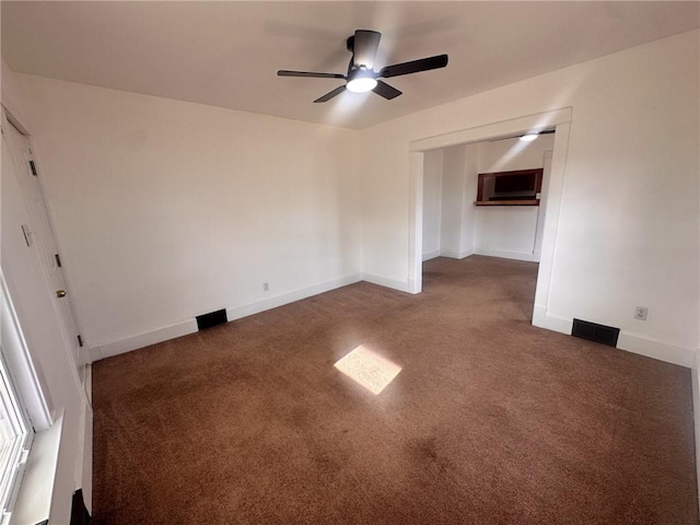 spare room with ceiling fan and dark colored carpet