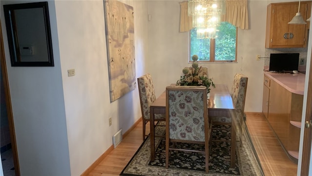 dining area with an inviting chandelier and light hardwood / wood-style flooring