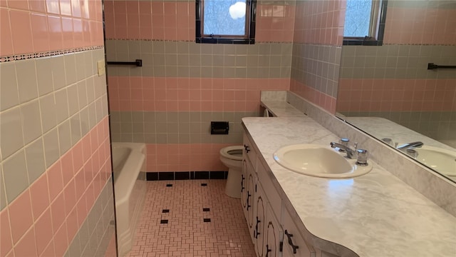 bathroom featuring a bathing tub, tile patterned floors, toilet, vanity, and tile walls