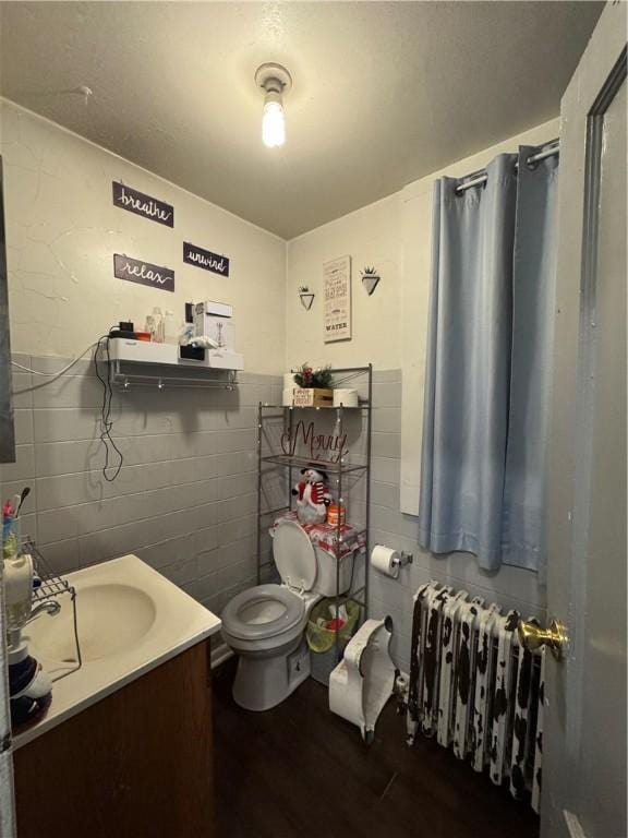 bathroom featuring radiator, hardwood / wood-style floors, vanity, and toilet