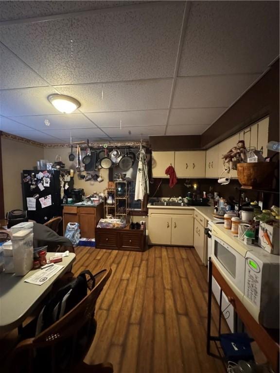 kitchen featuring a paneled ceiling, sink, black fridge, and hardwood / wood-style floors