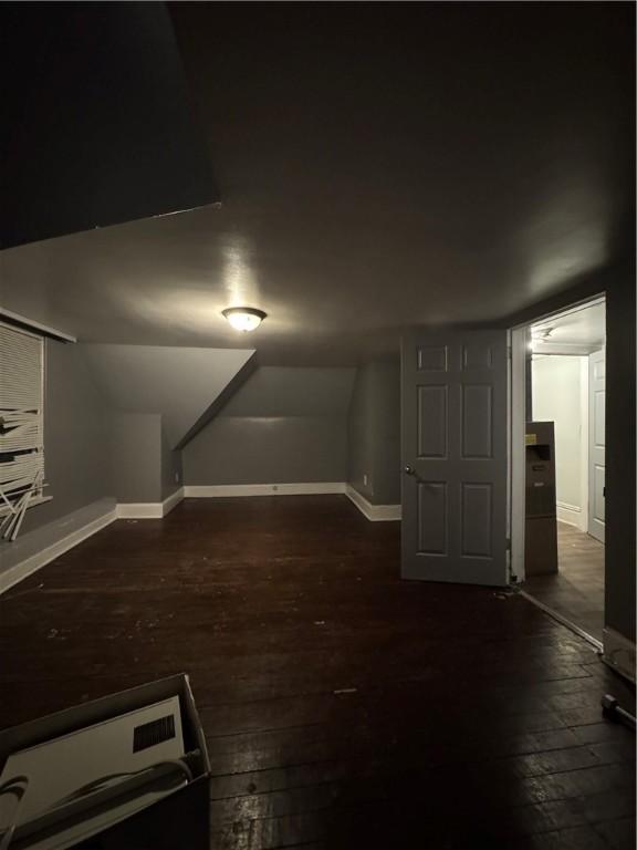 additional living space with dark hardwood / wood-style floors and lofted ceiling