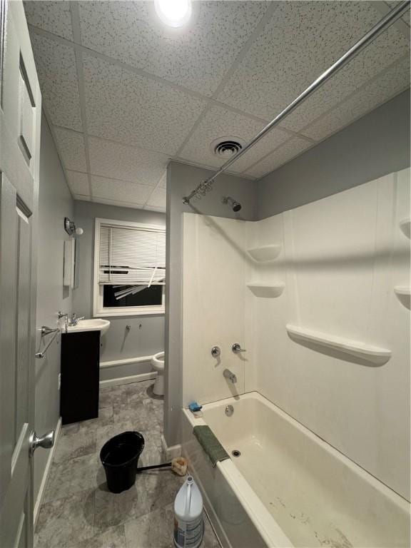 full bathroom featuring vanity, toilet, a drop ceiling, and tub / shower combination