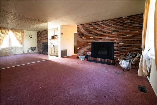 unfurnished living room with a fireplace, a textured ceiling, and carpet floors