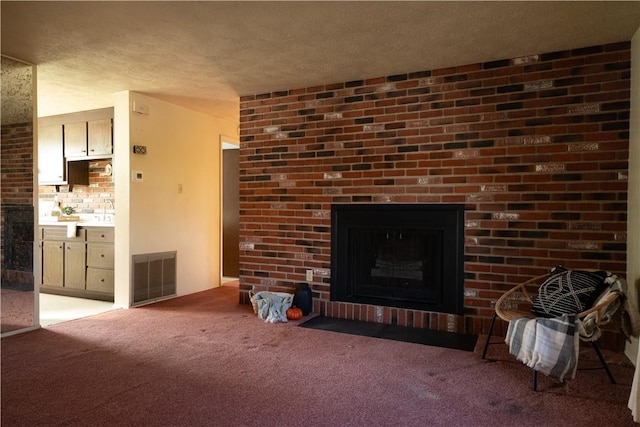 unfurnished living room with light colored carpet, a textured ceiling, and a brick fireplace