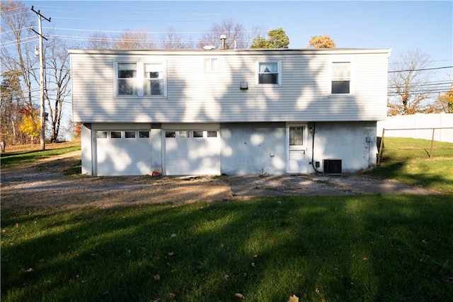 back of property featuring a lawn, a garage, and central air condition unit