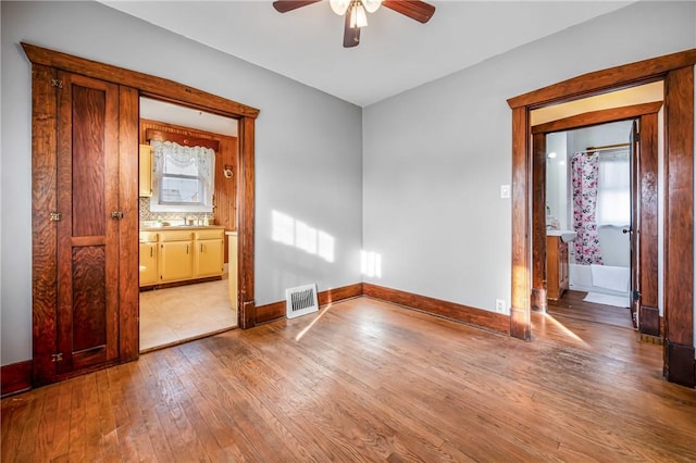 unfurnished bedroom featuring ensuite bath, ceiling fan, and light hardwood / wood-style floors