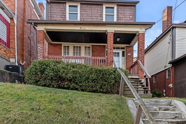 view of front of property with a front lawn, a porch, and central AC