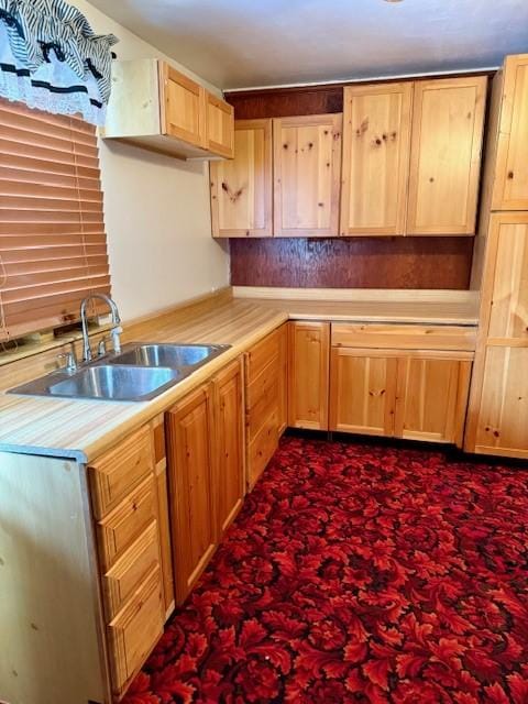 kitchen with light brown cabinets, sink, and dark carpet