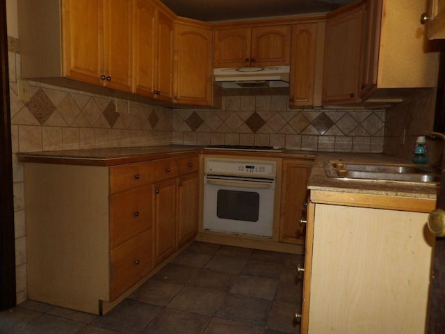 kitchen with oven, gas stovetop, decorative backsplash, and sink