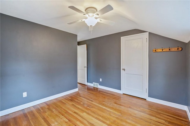 spare room with ceiling fan, light wood-type flooring, and vaulted ceiling