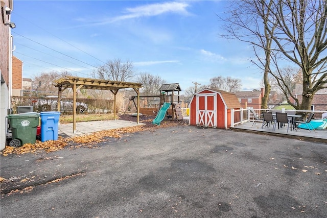 exterior space featuring a playground, a pergola, a patio, and a storage shed