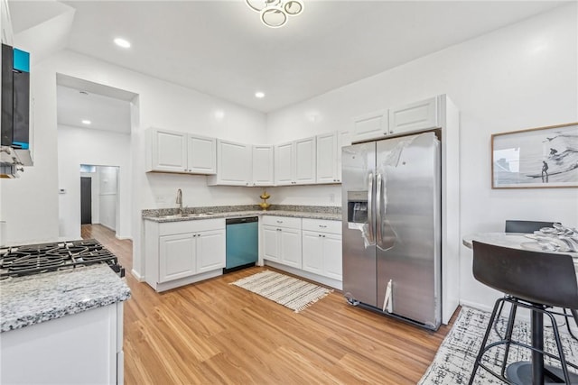 kitchen featuring stainless steel appliances, white cabinetry, light hardwood / wood-style floors, and light stone counters