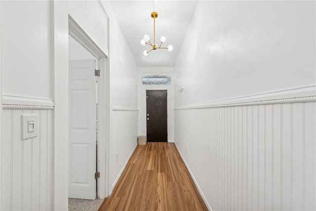 hall with hardwood / wood-style flooring and a notable chandelier