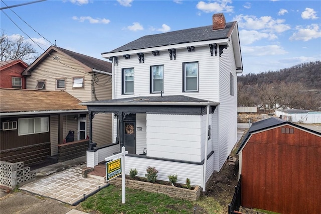 view of front of home featuring a storage unit and covered porch