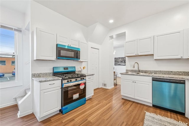 kitchen featuring gas stove, sink, dishwasher, light hardwood / wood-style floors, and white cabinetry