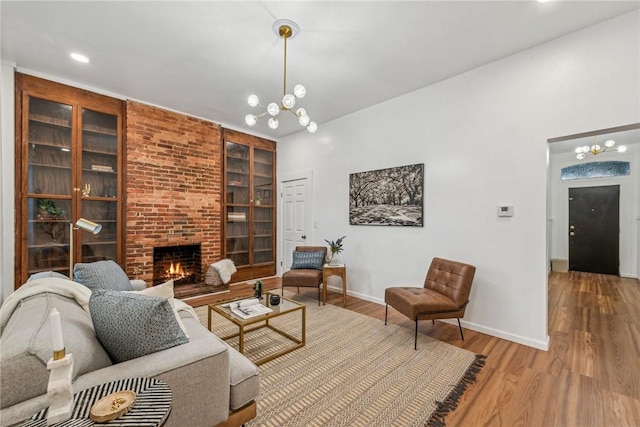 living room featuring a fireplace, hardwood / wood-style flooring, built in features, and a notable chandelier