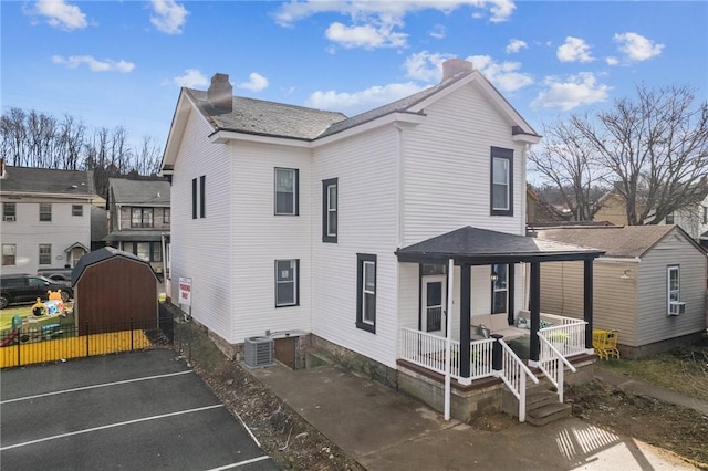 back of house with a porch, cooling unit, and central air condition unit