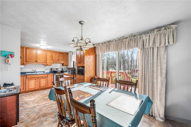 dining space with sink, a textured ceiling, and a notable chandelier