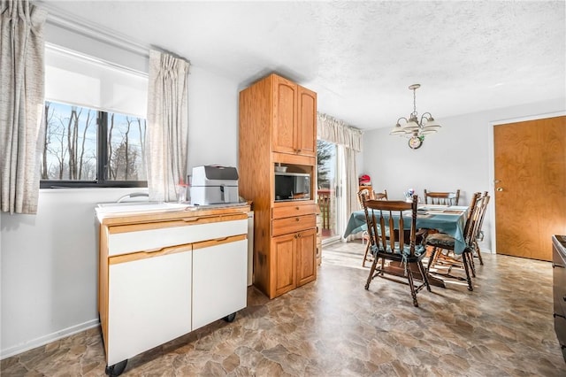 kitchen featuring a textured ceiling, pendant lighting, built in microwave, and a chandelier