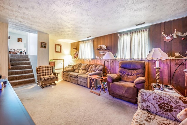 living room with plenty of natural light, carpet floors, a textured ceiling, and wooden walls