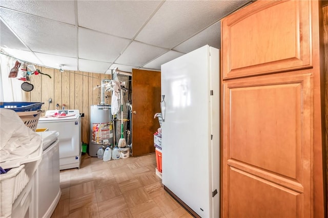 clothes washing area with separate washer and dryer, water heater, wooden walls, and light parquet floors