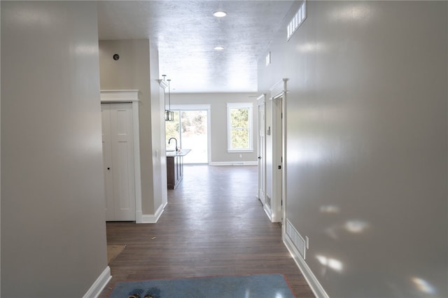 corridor featuring dark hardwood / wood-style floors, sink, and a textured ceiling