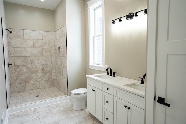 bathroom featuring vanity, toilet, tiled shower, and a wealth of natural light