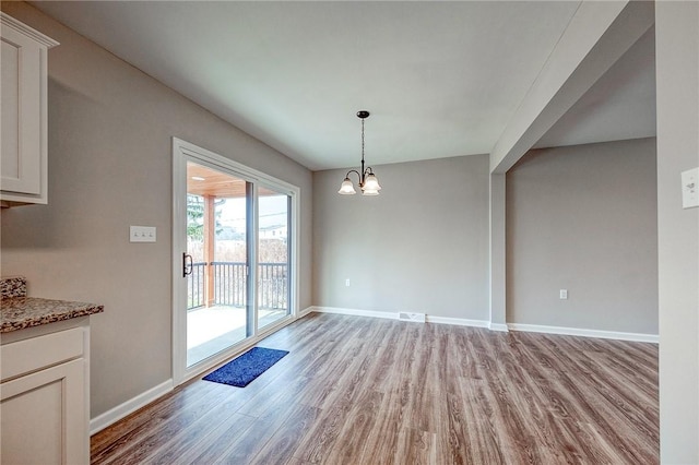 unfurnished dining area with light wood-type flooring and an inviting chandelier