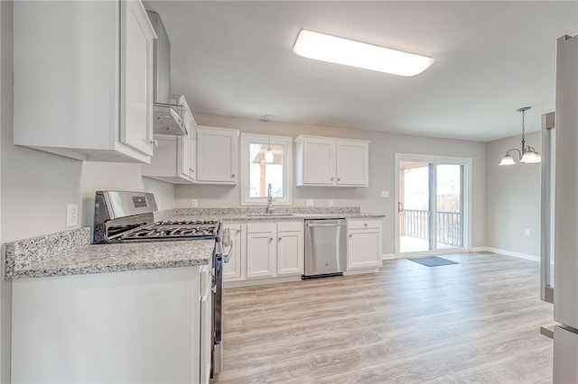 kitchen with appliances with stainless steel finishes, sink, an inviting chandelier, light hardwood / wood-style floors, and white cabinetry