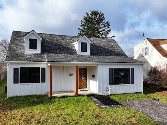 cape cod home featuring a porch and a front lawn