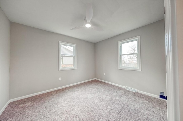 spare room featuring carpet, ceiling fan, and a wealth of natural light