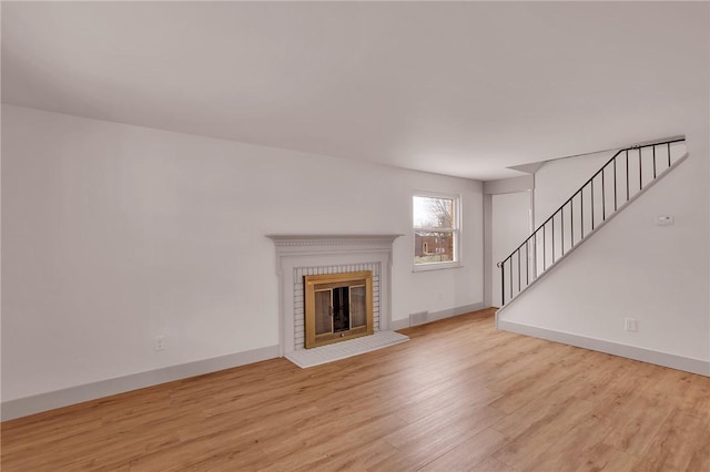 unfurnished living room featuring a brick fireplace and light wood-type flooring