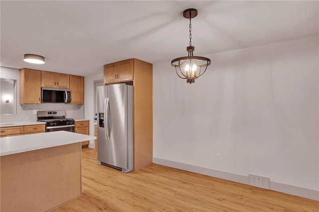 kitchen featuring an inviting chandelier, light hardwood / wood-style floors, appliances with stainless steel finishes, tasteful backsplash, and hanging light fixtures