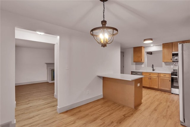 kitchen featuring decorative light fixtures, stainless steel appliances, decorative backsplash, sink, and kitchen peninsula