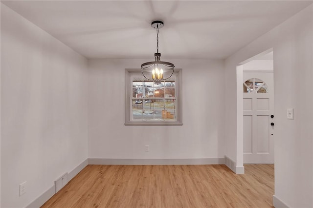 unfurnished dining area with light hardwood / wood-style flooring and a chandelier