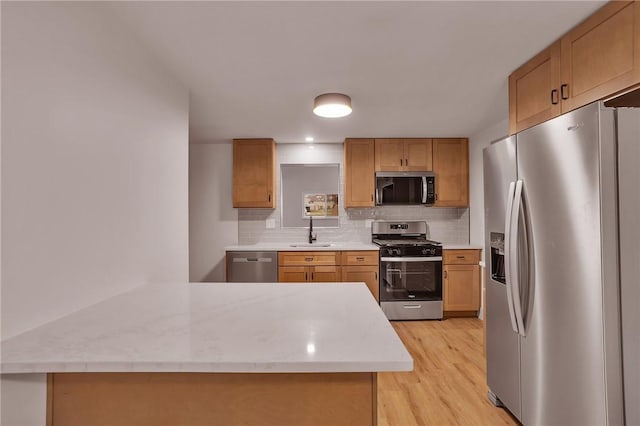 kitchen featuring kitchen peninsula, stainless steel appliances, decorative backsplash, light hardwood / wood-style flooring, and sink