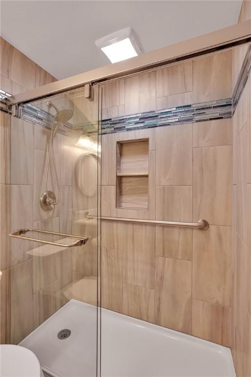 bathroom featuring toilet and a shower with shower door