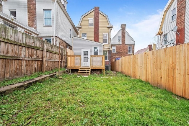 rear view of house featuring a lawn and a deck