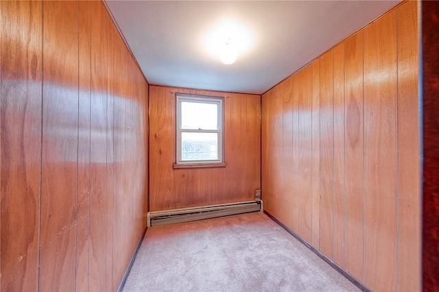 spare room with wooden walls, light carpet, and a baseboard heating unit