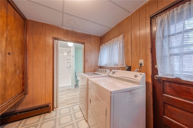 clothes washing area featuring separate washer and dryer, plenty of natural light, and wooden walls